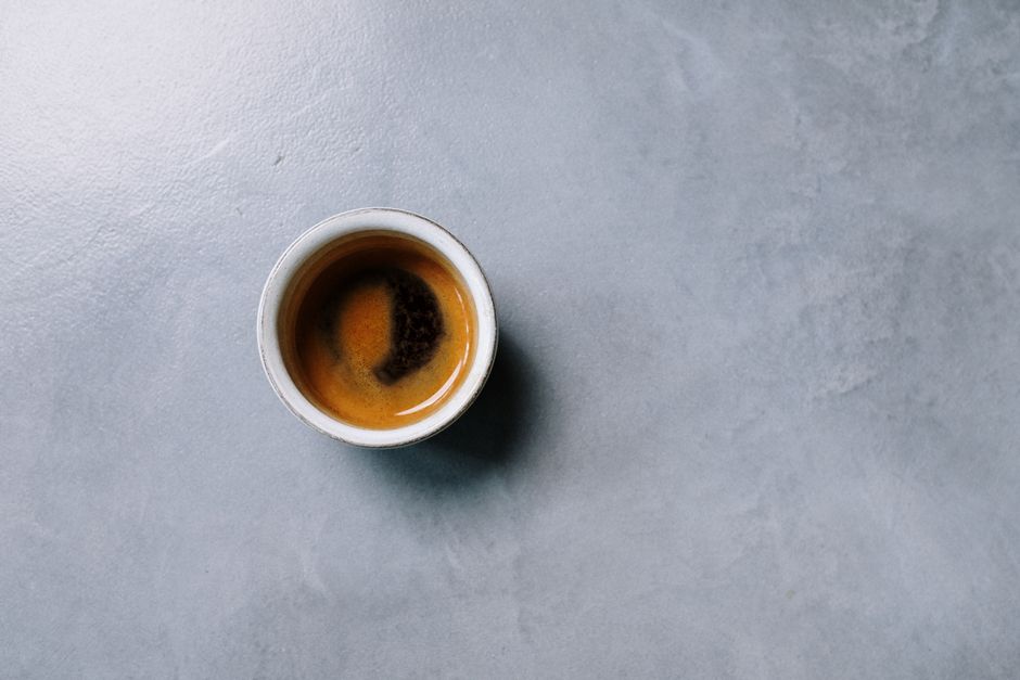 Top view of a cup of espresso on a textured grey surface, minimalist style.