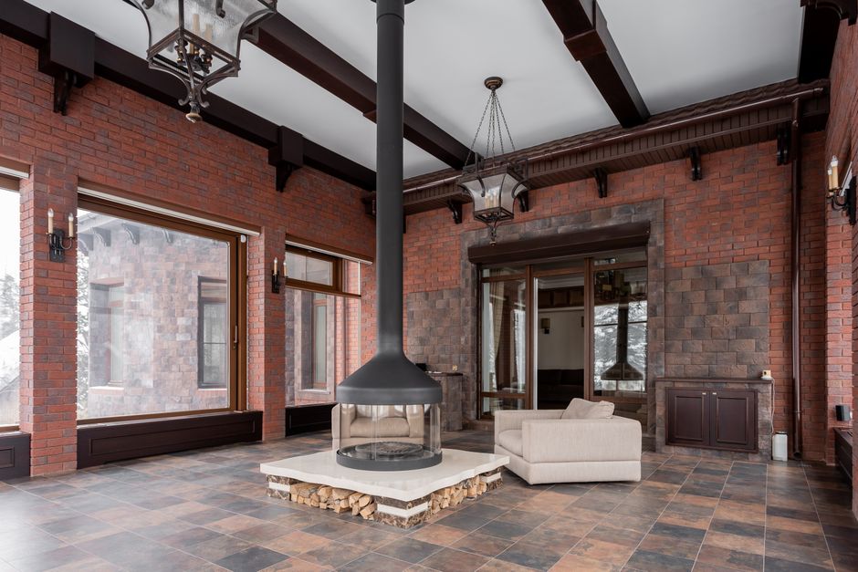 Spacious modern interior with a central fireplace and brick walls, elegantly lit by natural daylight.