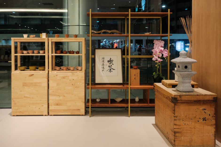 A stylish tea display in a serene cafe setting featuring shelves with pottery, calligraphy, and decor.