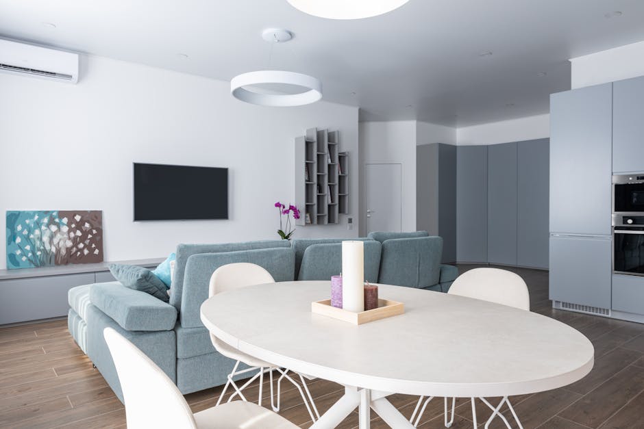 Modern interior of comfortable open plan kitchen and living room with gray sofa and TV with gray shelves hanging on wall